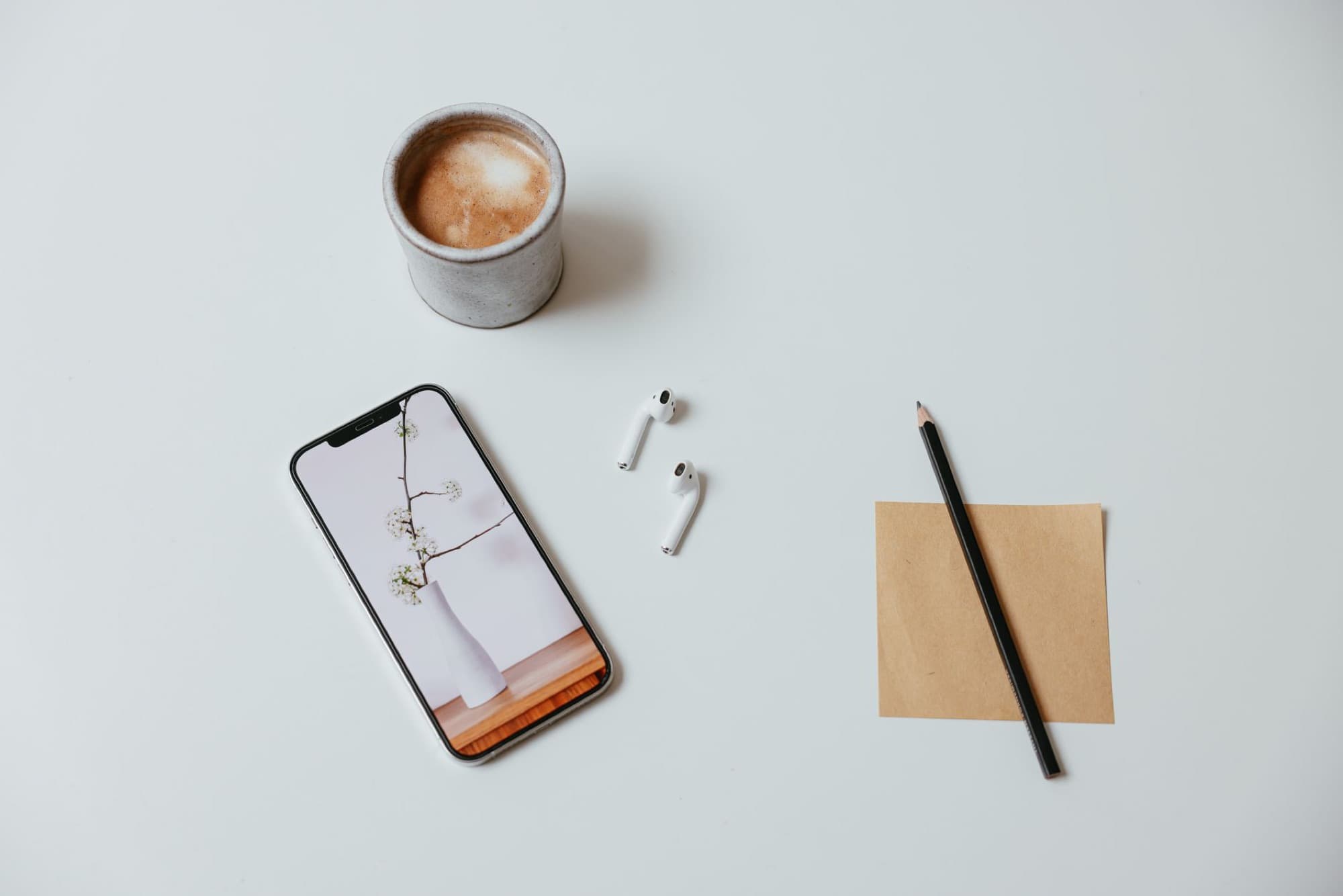 A phone, notepad, and coffee on a working desk