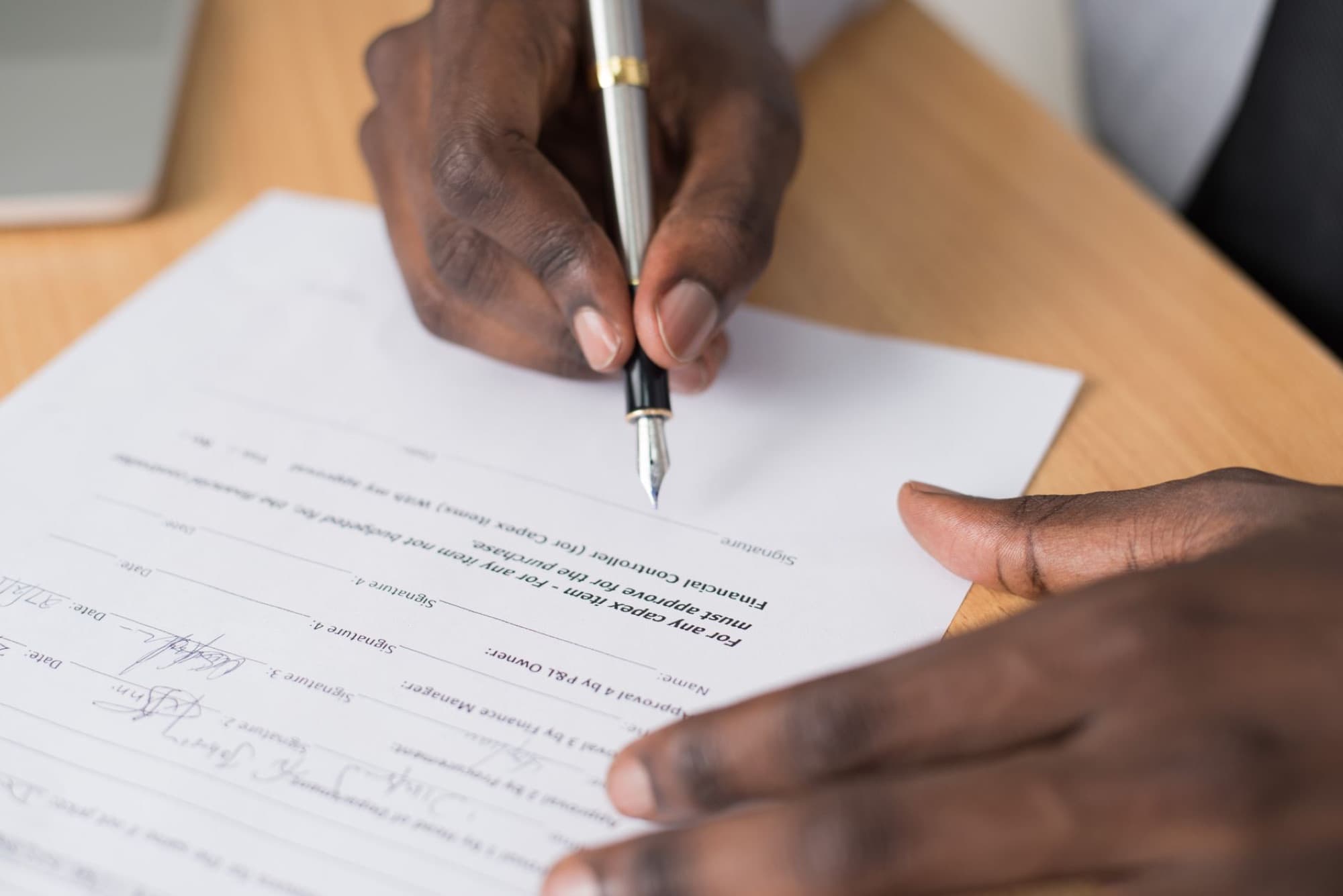 A hand signing a document with a fountain pen