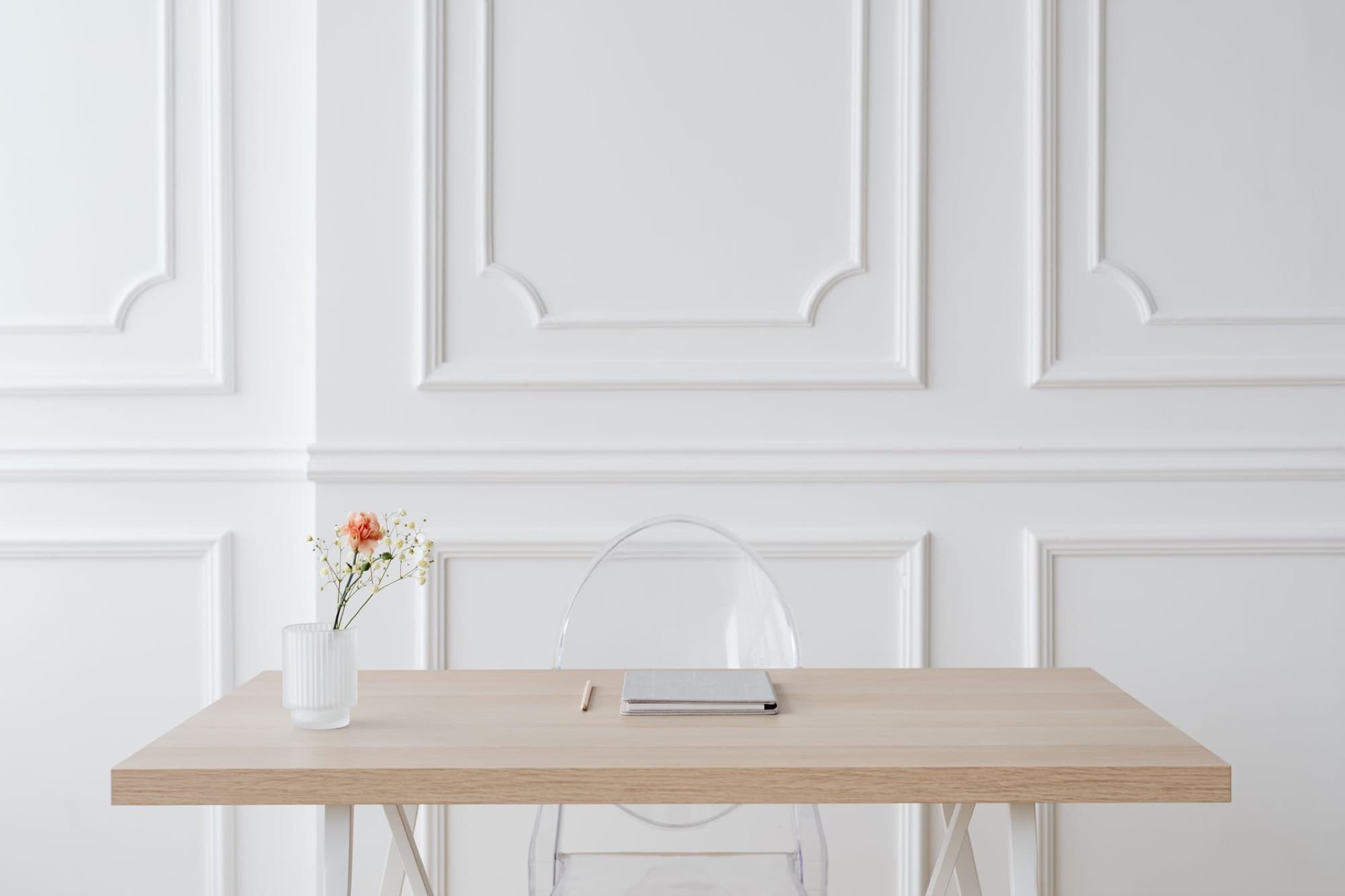 Light falling across a desk with a notebook and a single pen