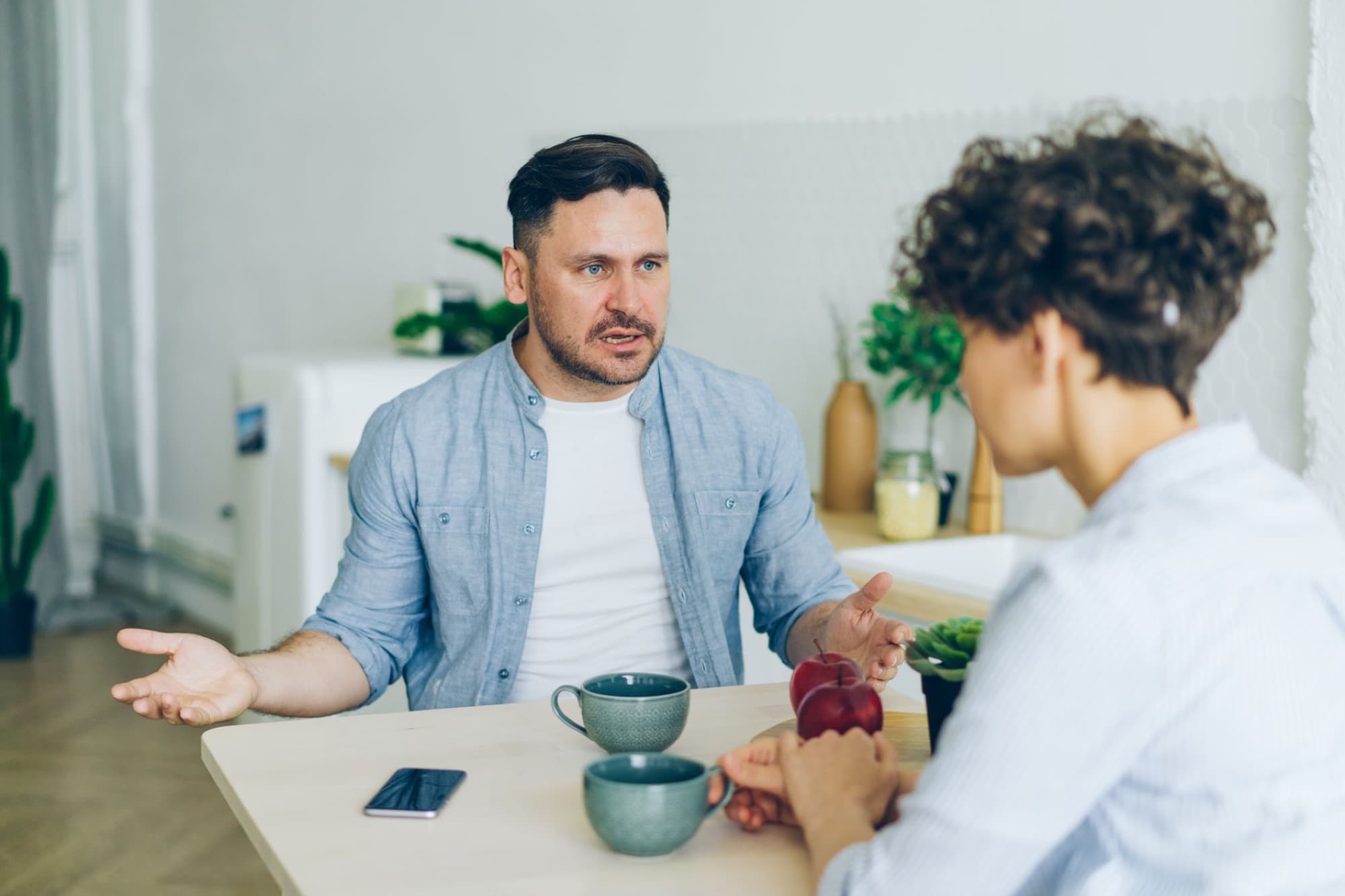Two people talking across a kitchen table